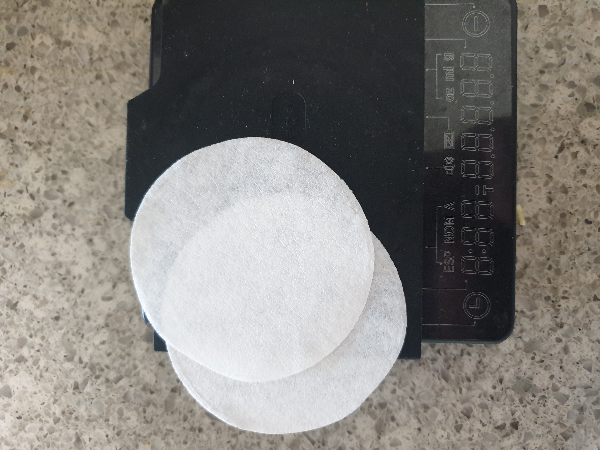 검은색 저울 위에 에어로프레스 종이 필터 2장이 올려져 있다.