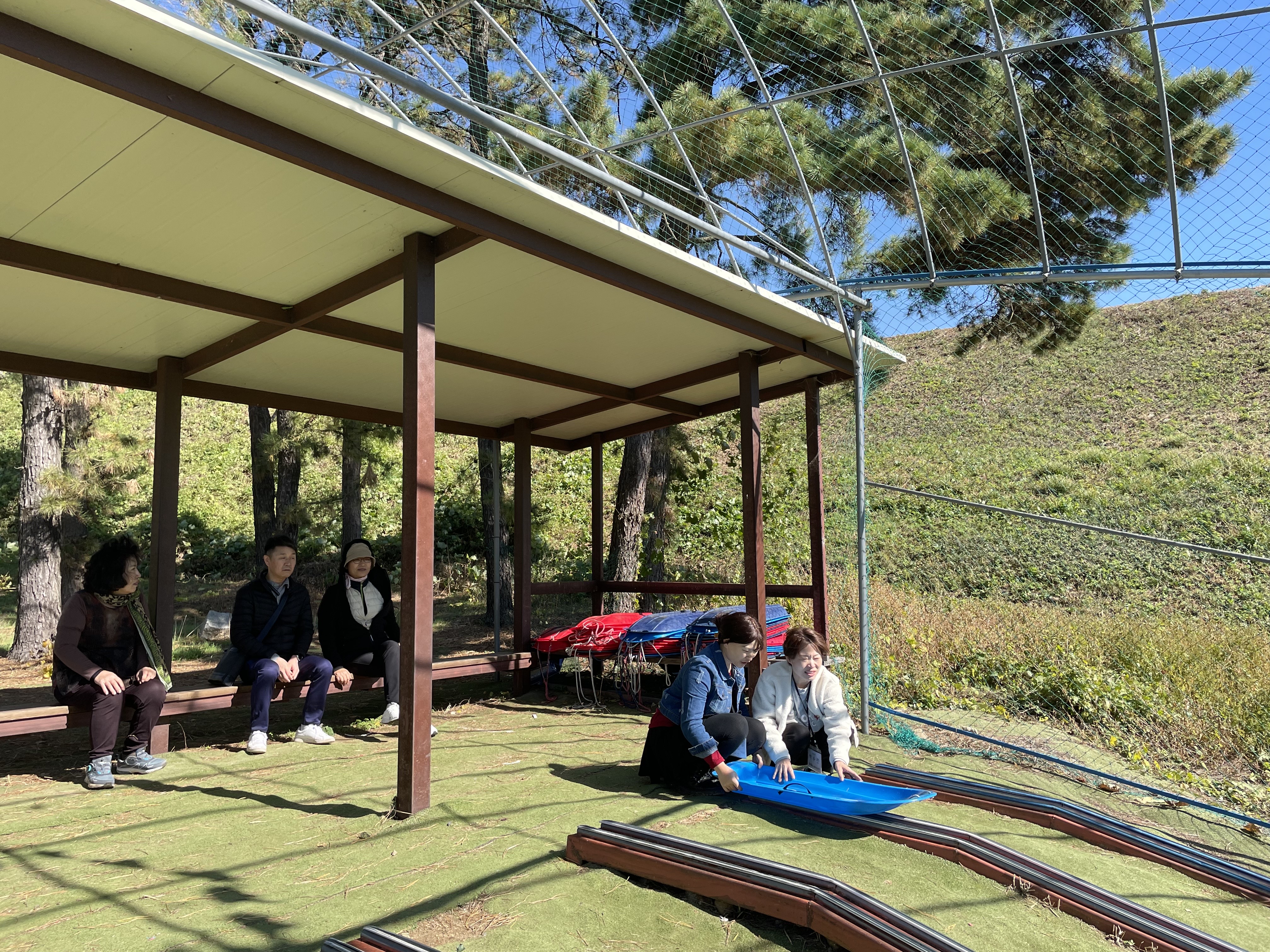 사진설명: 레일썰매 타는 방법을 설명하는 쉼터직원과 설명을 듣는 회원들 모습