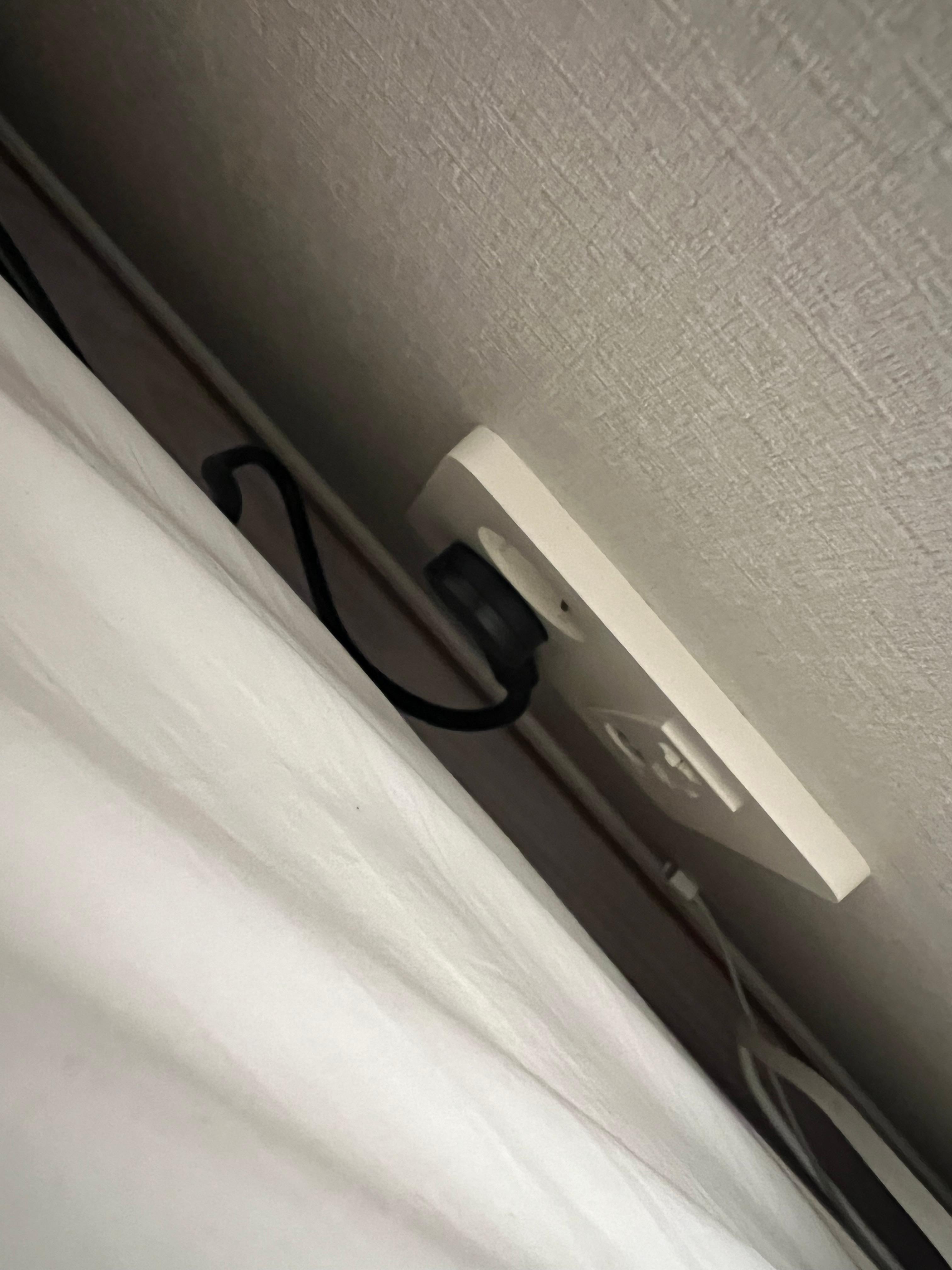 원스탑 납작멀티탭 침대 벽 사이 실사용 전경 — 침대 프레임과 벽 사이 협소한 공간에 설치된 실제 장착 모습
