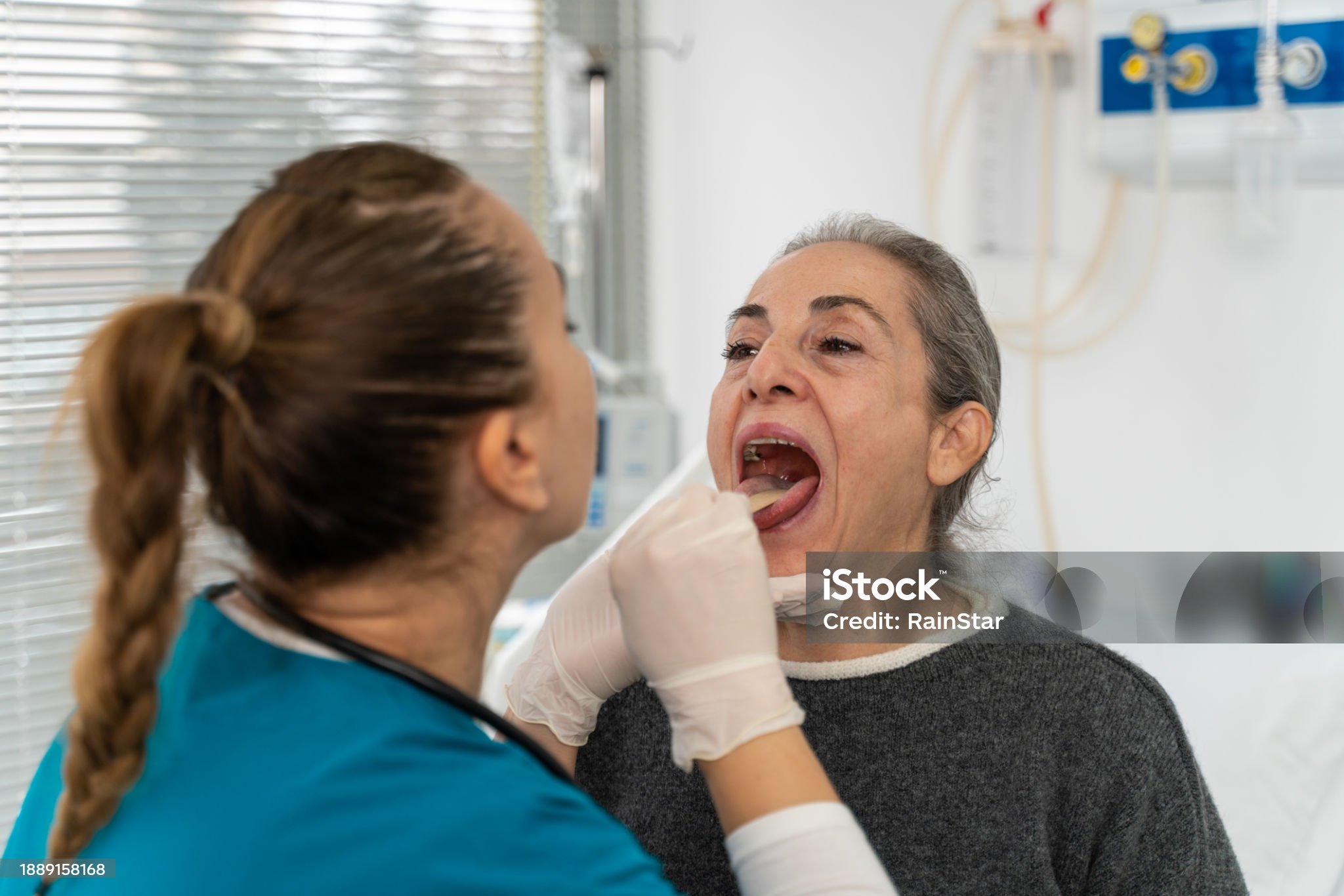 노인이 입을 벌리고 의사가 입안을 살핀다