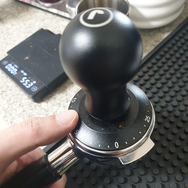 탬퍼가 포터필터 위에 올려져 있다. 옆에는 저울도 보인다.