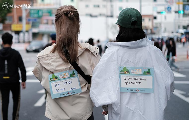 서울길에 바라는 메시지를 적은 '메시지 보드'를 등에 부착한 시민들 ⓒ김아름