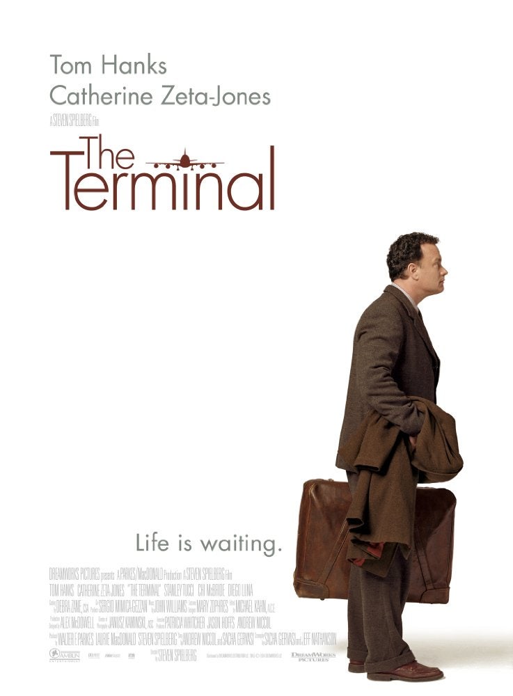 영화 '터미널(The Terminal, 2004)'의 메인 포스터. 깨끗하고 하얀 배경을 바탕으로, 오른쪽에는 주인공 빅터 나보스키(톰 행크스 배우)가 서 있는 뒷모습을 담고 있다. 그는 짙은 갈색 정장 차림에 갈색 가죽 가방을 들고 있으며, 코트를 팔에 걸치고 왼쪽(비행기가 있는 방향)을 바라보고 있다. 왼쪽 상단에는 영화 제목인 "The Terminal"이 크고 짙은 갈색 폰트로 적혀 있으며, 'The' 자리에 작은 비행기 아이콘이 그려져 있다. 그 위로 배우 이름인 "Tom Hanks", "Catherine Zeta-Jones"가 차례로 적혀 있다. 제목 아래에는 영화의 슬로건인 "Life is waiting.(인생은 기다림이다.)"이라는 문구가 회색 폰트로 적혀 있으며, 하단에는 제작사 및 출연진 정보가 담긴 크레딧과 파라마운트 로고 등이 표시되어 있다.