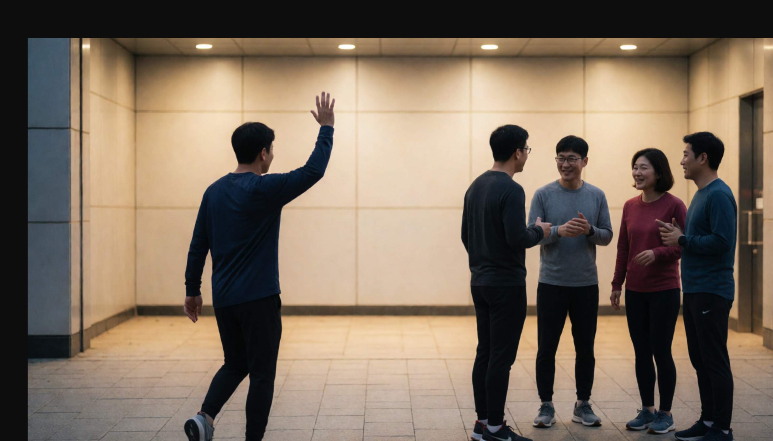 실내 통로에서 한 사람이 손을 들어 작별하고 네 명이 대화하는 모습