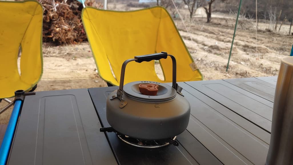 캠핑테이블에서 물이 끓여지는 주전자