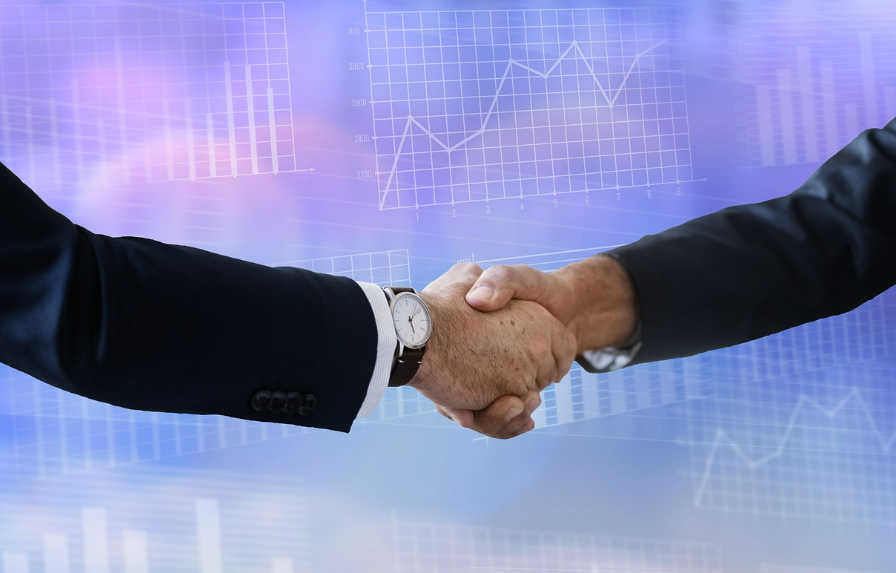 차트가 띄워진 화면 앞에서 악수하는 두 손