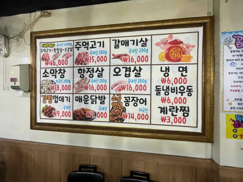 벽면 메뉴판 모습 꼼장어, 오겹살 등 다양한 메뉴가 적혀 있는 모습
