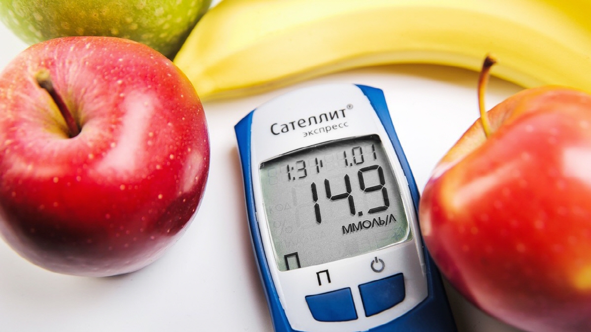 혈당측정기와 사과, 바나나 등 과일이 함께 놓인 이미지