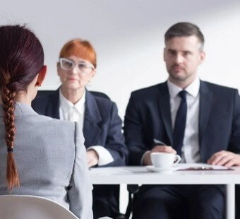 머리를-길게-따고-옅은-회색-상의를-입은-여성-지원자가-두명의-남여-면접관-앞에서-자신있게-대답하는-모습