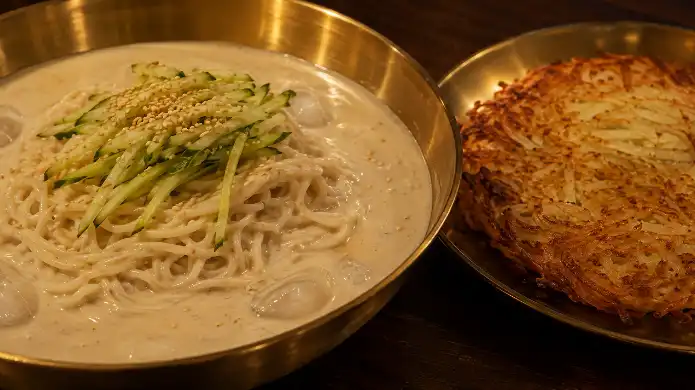 노릇하고 바삭하게 구워진 감자전과 놋그릇 대접에 고소하게 담긴 콩국수의 디테일