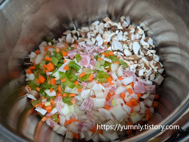 Sautéing chopped mirepoix vegetables and bacon in a large pot with olive oil