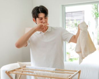 남자가 빨래에서 냄새가 나 코를 막고 있는 모습