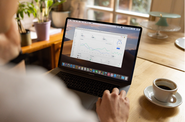 노트북 화면에 그래프와 통계 데이터가 표시되고 있으며, 한 사람이 이를 분석하고 있는 모습