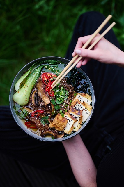 접시에 건강한 재료로 만든 음식이 놓여져있다. 청경채, 버섯, 두부 등이 보인다. 아시안 음식인 듯 나무 젓가락으로 음식을 집으려고 한다.