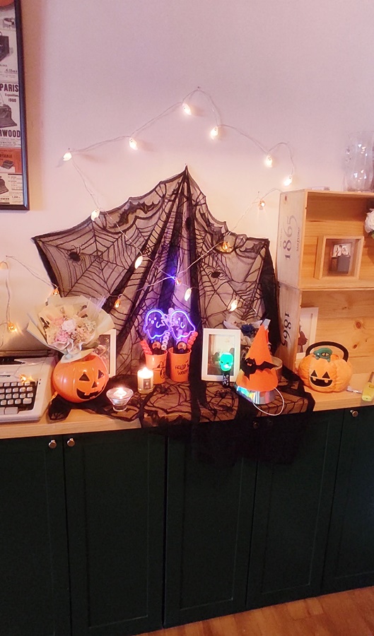 현관쪽 복도를 장식한 할로윈소품 거미줄 모양 천에 여러 조명과 소품을 균형있게 장식함