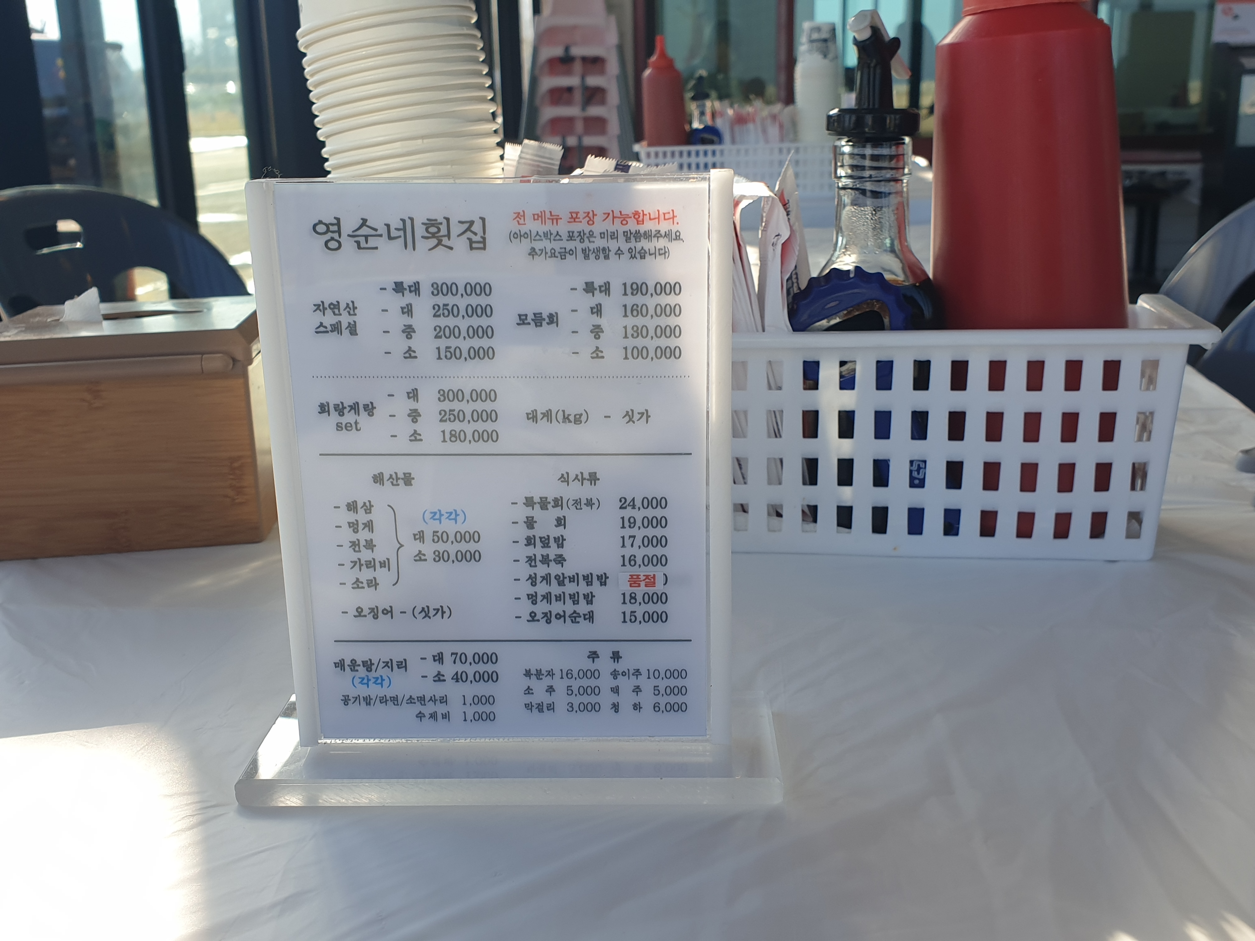 테이블 위에 메뉴판, 냅킨, 물컵 그리고 양념통 등이 올려져 있다.