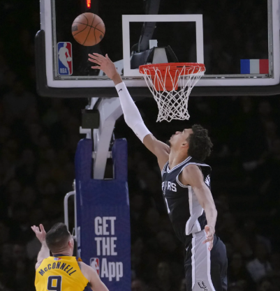 농구선수가 슛을 하고 상대방이 블로킹을 하고 있다.