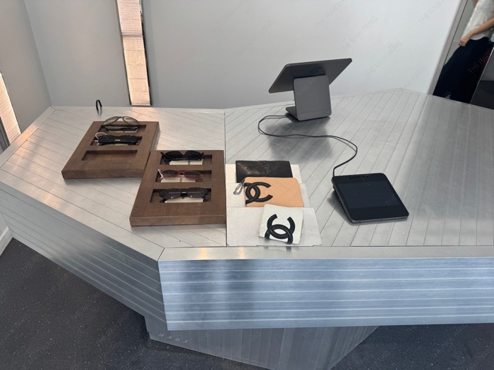Vintage Chanel wallets and designer sunglasses displayed on a metallic counter at Nuovo Paris ❘ Portefeuilles Chanel vintage et lunettes chez Nuovo⁠