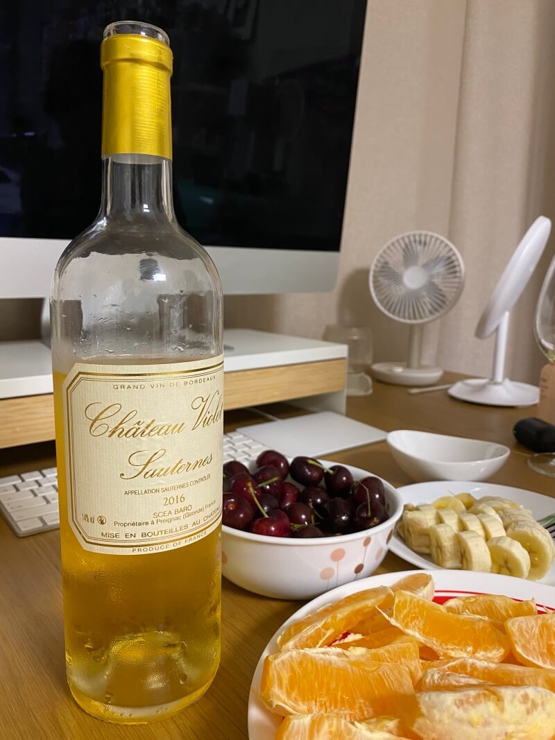 소테른 귀부와인 한 병과 체리 오렌지 바나나가 놓여있음