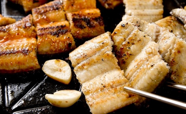 검은색 철판위에 구워진 장어가 올라가 있다.