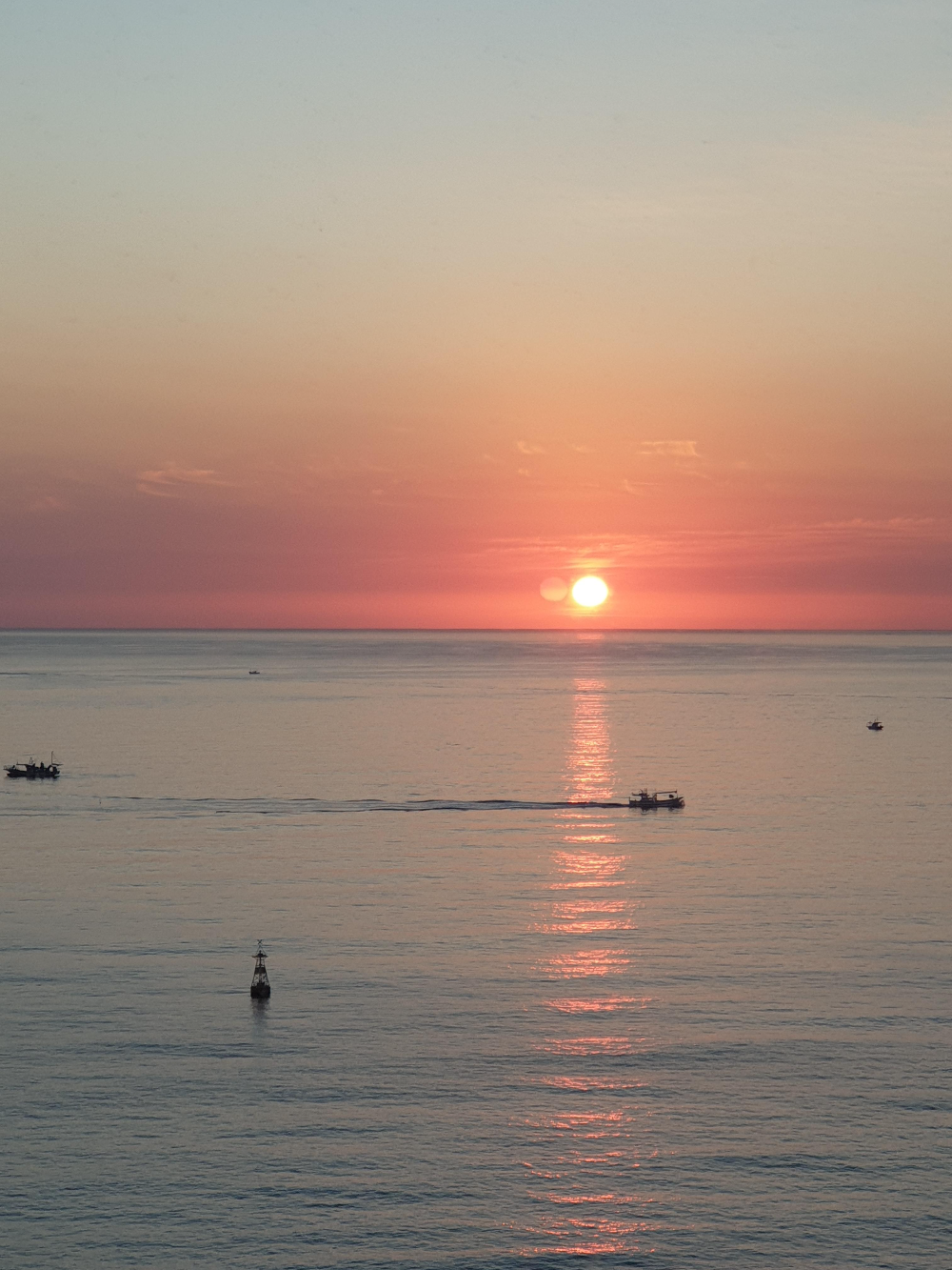 붉은 태양의 긴 불빛이 바다를 비추고 있다. 수평선을 따라 붉은 빛이 퍼진다.