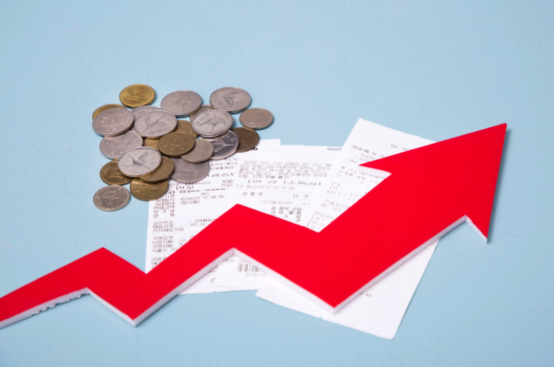 동전들과 영수증이 놓여있고 상승그래프가 빨갛게 그려져 있다.