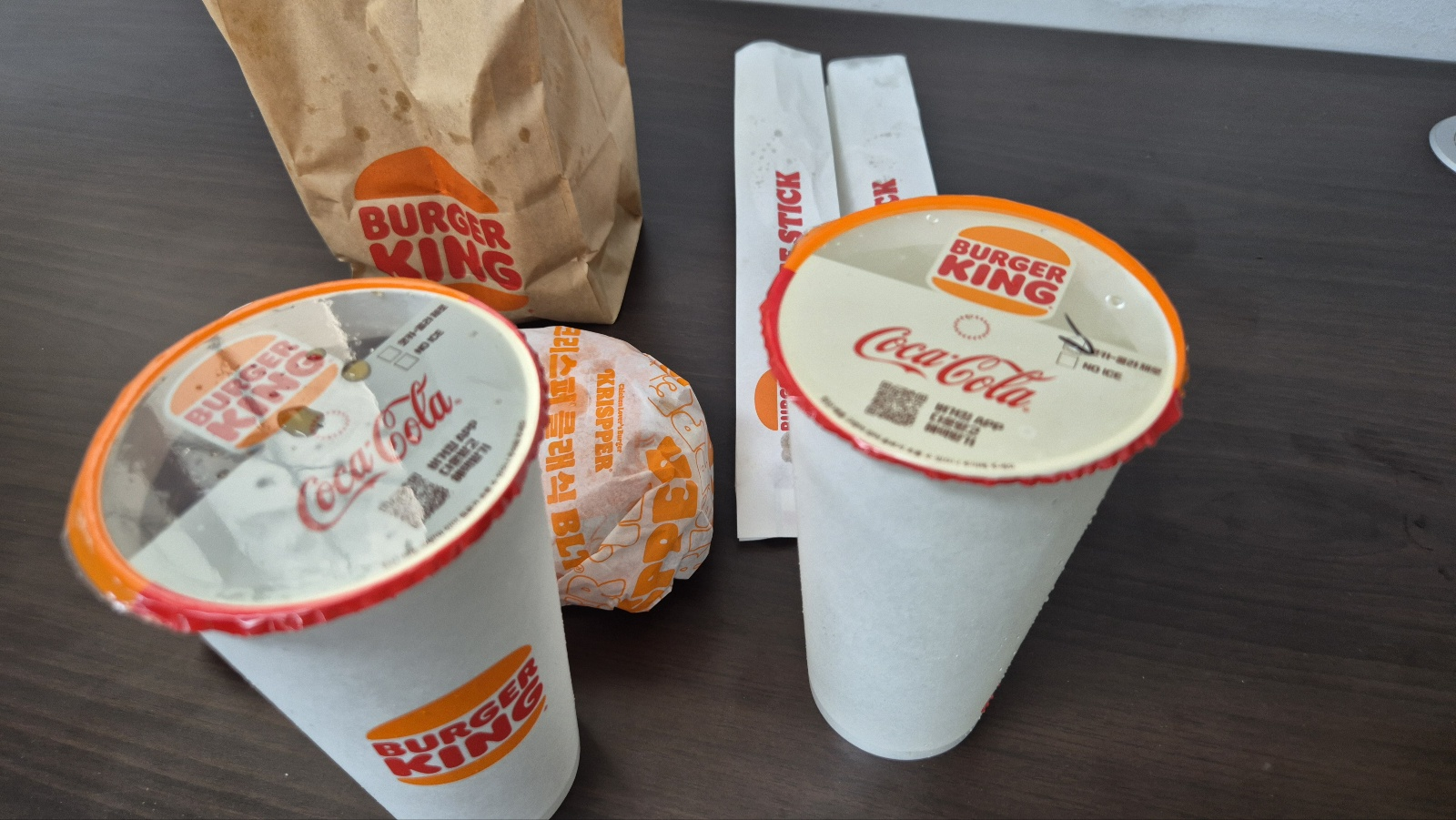 크리서퍼 구성품인 버거와 음료등이 책상위에 있다.