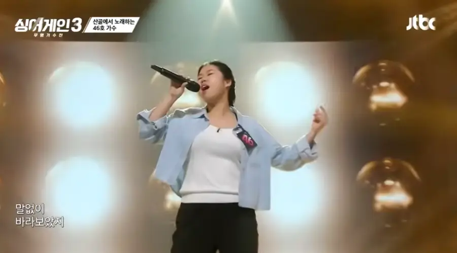 싱어게인3-
회색 배경 무대위 청색 셔츠에 흰티를 받쳐입고 검은마이크를 오른손으로 들고 긴머리를 뒤쪽 하나로 묶고 왼손은 위로들고 노래하는 46호의 왼족모습