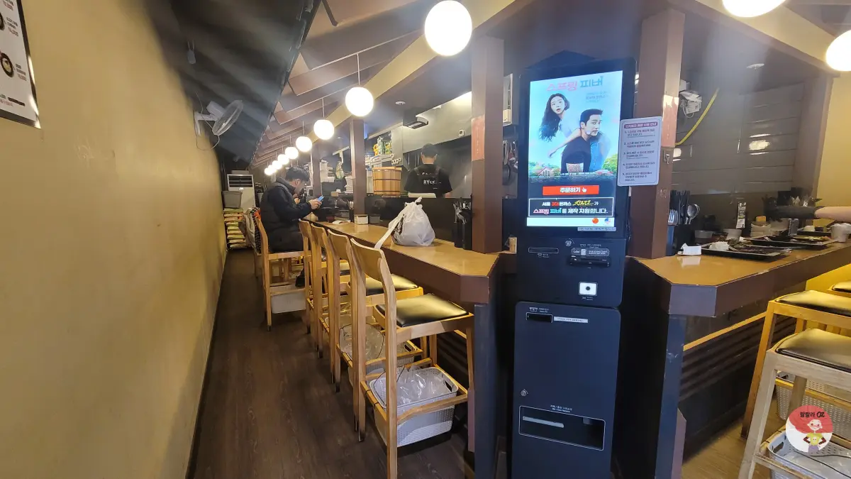 경기 남양주 긴자료코 다산점 좁고 긴 식당 내부 모습-나무 의자가 줄지어 놓인 바 스타일의 긴 카운터가 보인다.