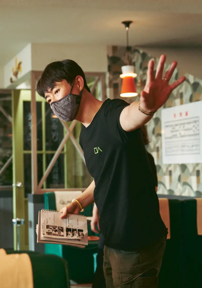 영화 밀수 세트장에서 검은 반팔티에 마스크를 쓰고 있는 류승완 감독