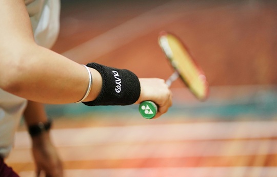 손목에 땀흡수 밴드를 차고 배드민턴 라켓을 잡고 있다.