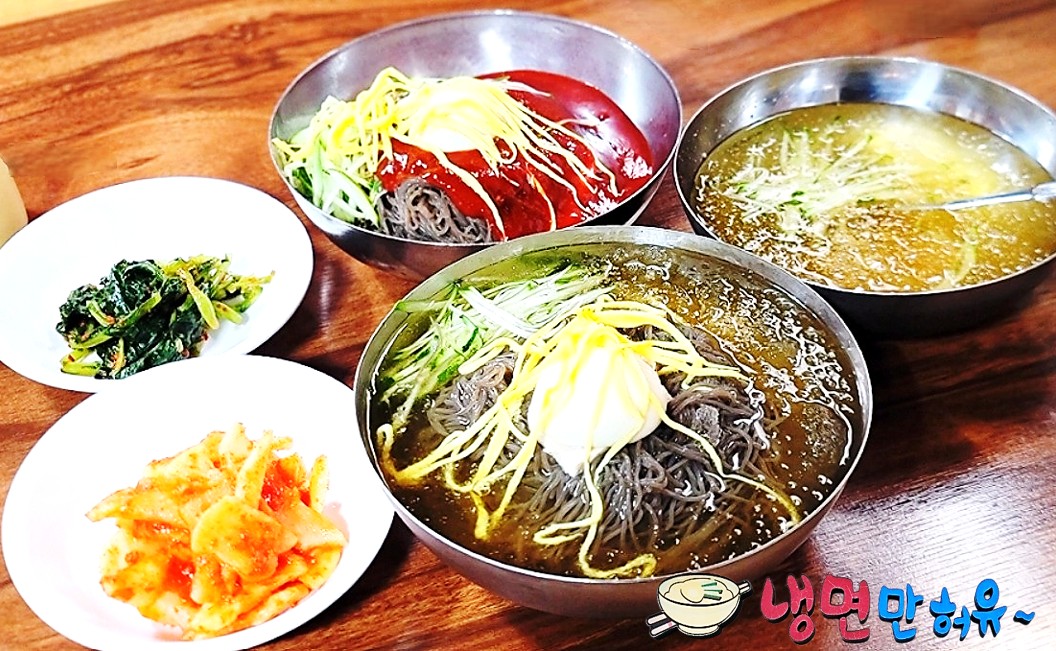 서산 냉면만허유 원조부석식당의 고명이 잔뜩 올라간 물냉면과 비빔냉면, 그리고 비빔냉면의 생강육수, 열무김치와 무김치가 테이블에 올려져 있는 모습