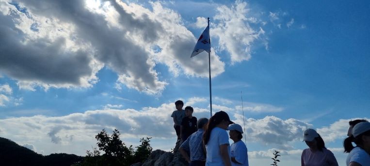 관모봉 정상, 펄럭이는 태극기, 푸른 하늘, 회색 구름, 인증샷 찍는 남 여 무리