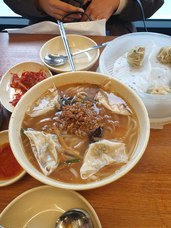 테이블 위에 이미 먹기 시작한 만두와 막 나온 칼국수가 놓여있다.