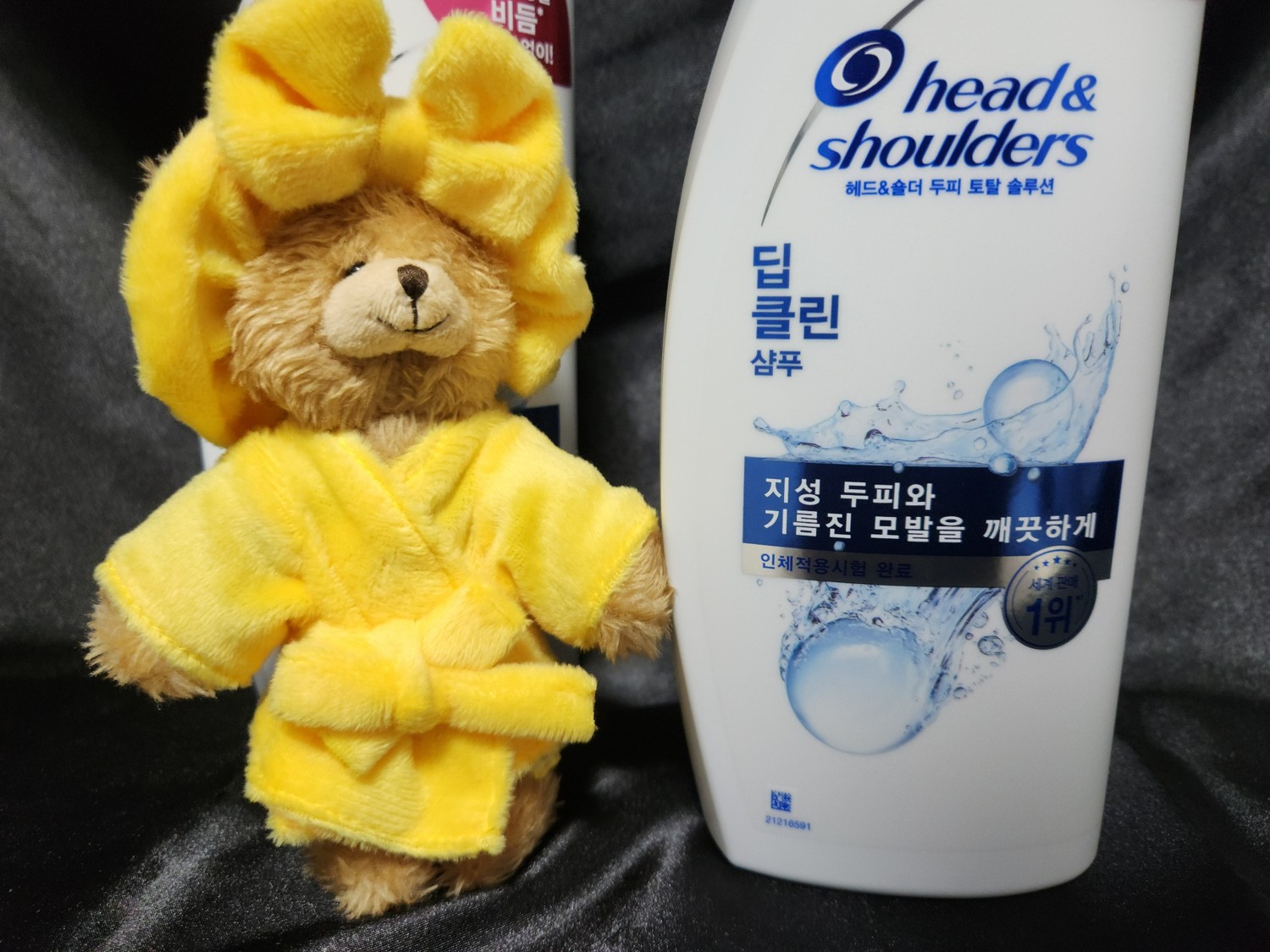 샴푸 옆에 샤워 복장을 입은 곰 인형이 있다