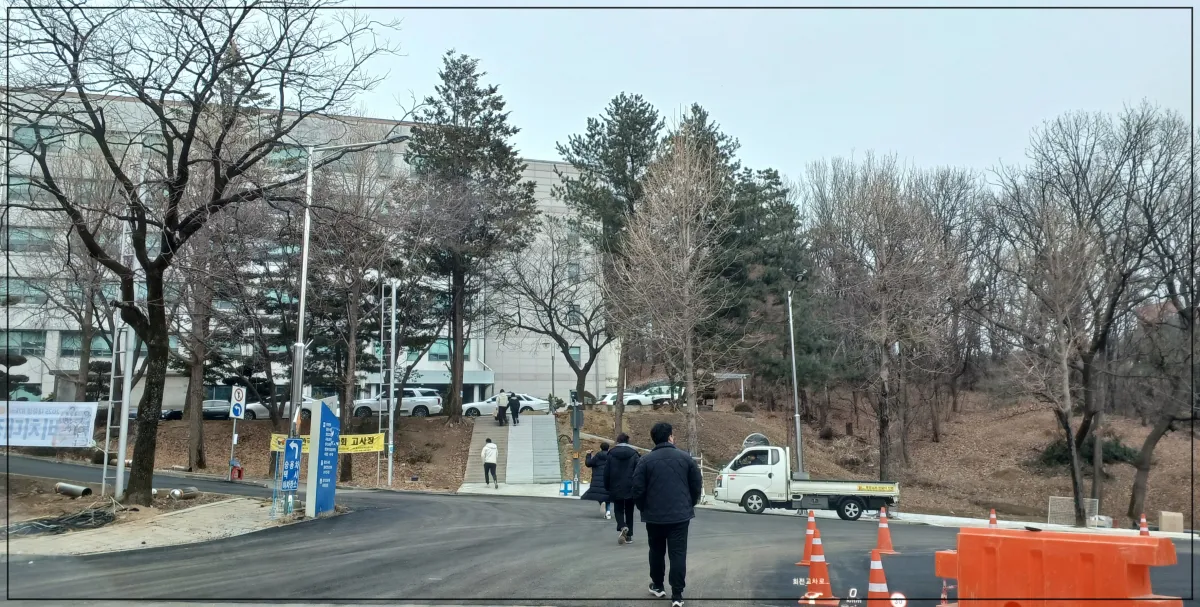 대학-안에-건물안으로-사람들이-들어가는-모습-사람이-많지는-않음-겨울인지-검은색-두꺼운-잠바를-입은-사람들-나무들은-앙상함