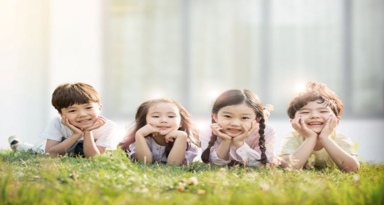 4명의 아이들이 풀밭에서 포즈를 취하고 있음