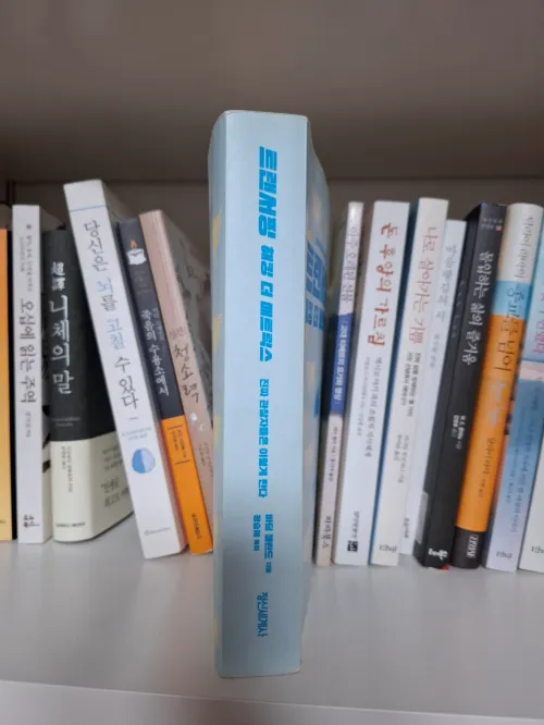 책장에 꽂힌 다른 책들 사이에서 눈에 띄게 앞으로 불쑥 나와 있는 해킹 더 매트릭스 도서 (The book 'Hacking the Matrix' protruding noticeably from others on a bookshelf)