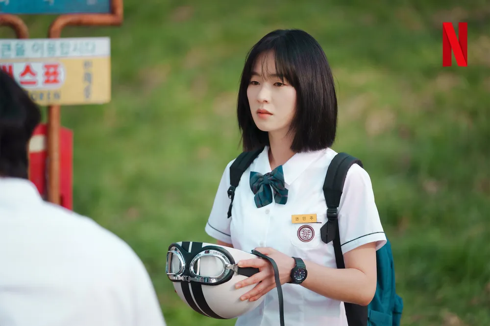 버스 정류표지판이 있는 야외에 단발머리와 고복을 입고 헬멧을 들고 서 있는 드라마 너의 시간 속으로의 권민주 캐릭터
