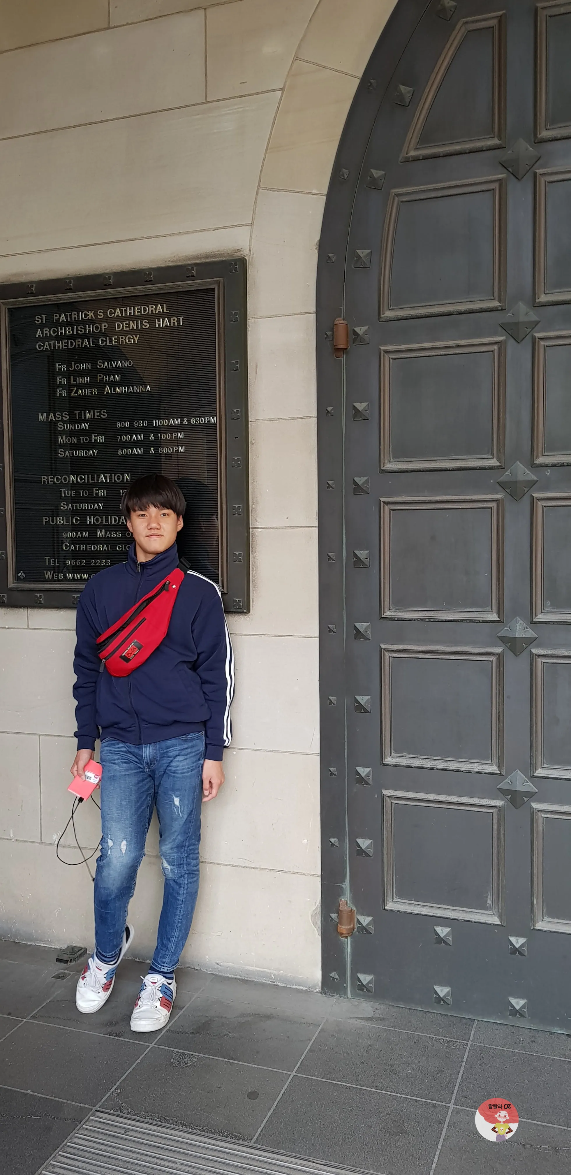 호주 멜버른 세인트 패트릭 대성당 안내판 앞에서 찍은 사진, 대형 금속문과 성당 정보판이 보인다