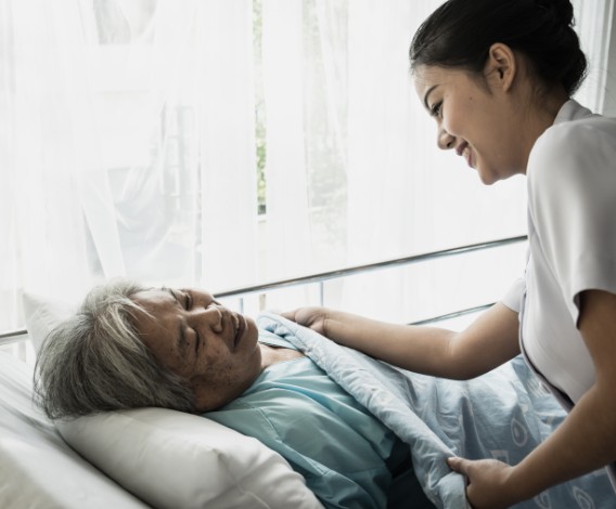 편안한 잠자리를 위해 이불을 덮어드리는 요양보호사