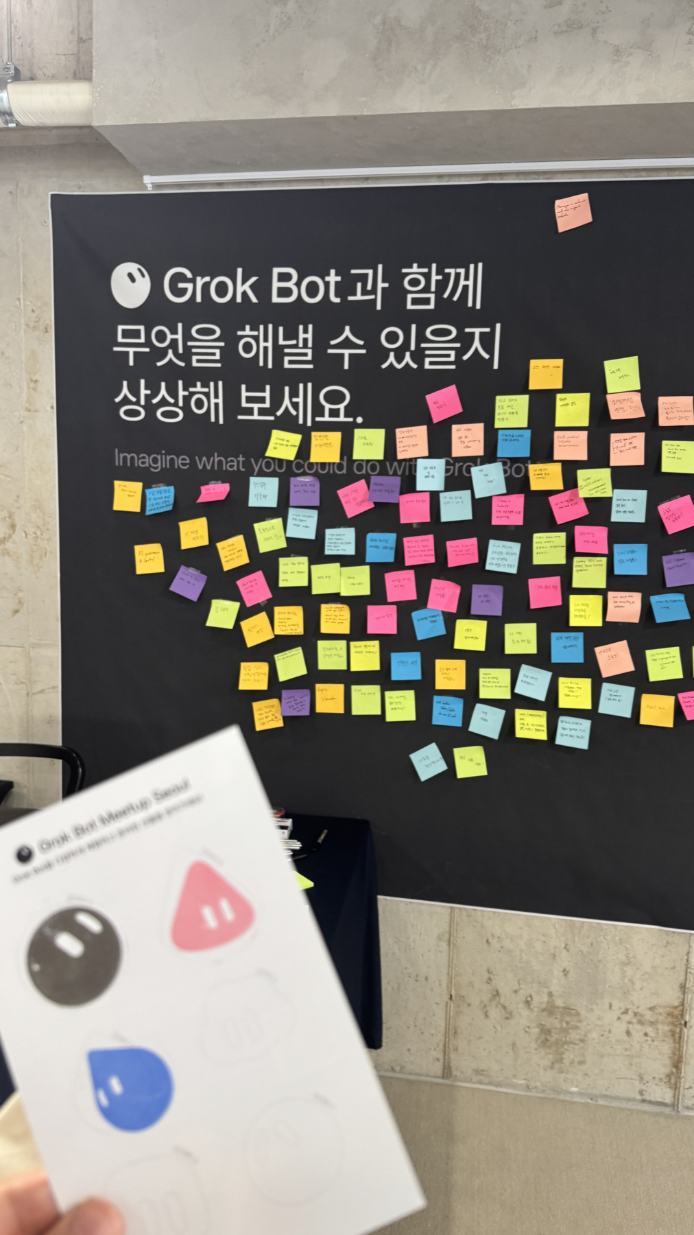 Grok Bot과 함께 할 일을 상상해 보라는 문구와 여러 포스트잇이 붙은 벽