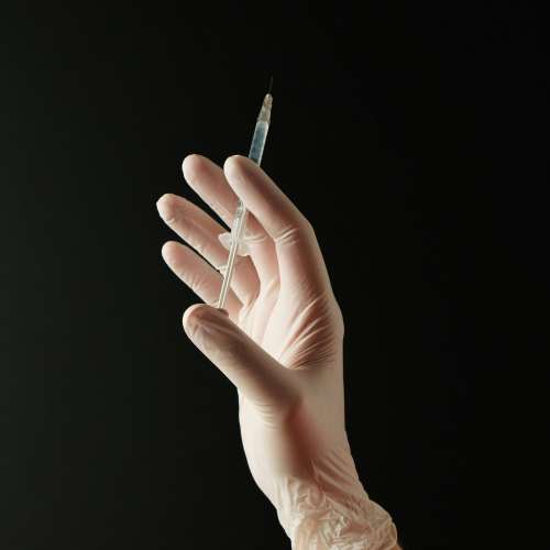 의료용 장갑을 낀 손이 주사기를 들고 있는 모습