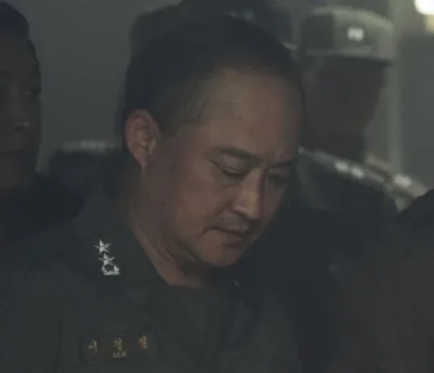 대머리에 군복을 입고 서 있는 영화 서울의 봄에서 서정필을 연기하는 김정팔