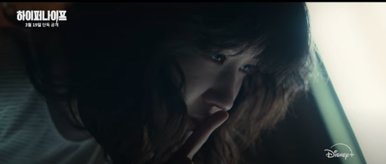 어둠 속에서 조용히 숨을 죽이며 긴장한 모습의 여성.