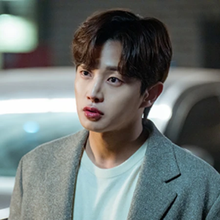 주차된 차를 배경으로 회색 자켓에 갈색 머리를 하고 있는 오늘도 사랑스럽개의 강은환 캐릭터