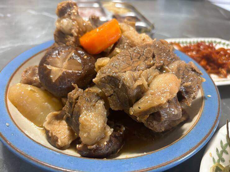 접시에 완성된 갈비찜이 담겨 있는 사진이다.
갈비와 버섯, 감자, 당근이 함께 있다.
