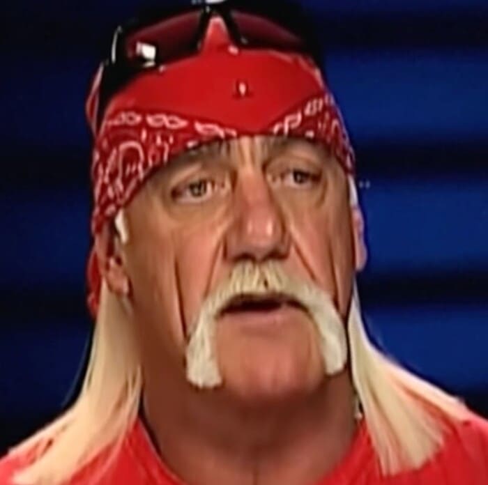 빨간 반다나와 선글라스를 머리에 얹은 헐크 호건이 인터뷰 장면에서 진지하게 말을 이어가는 모습.