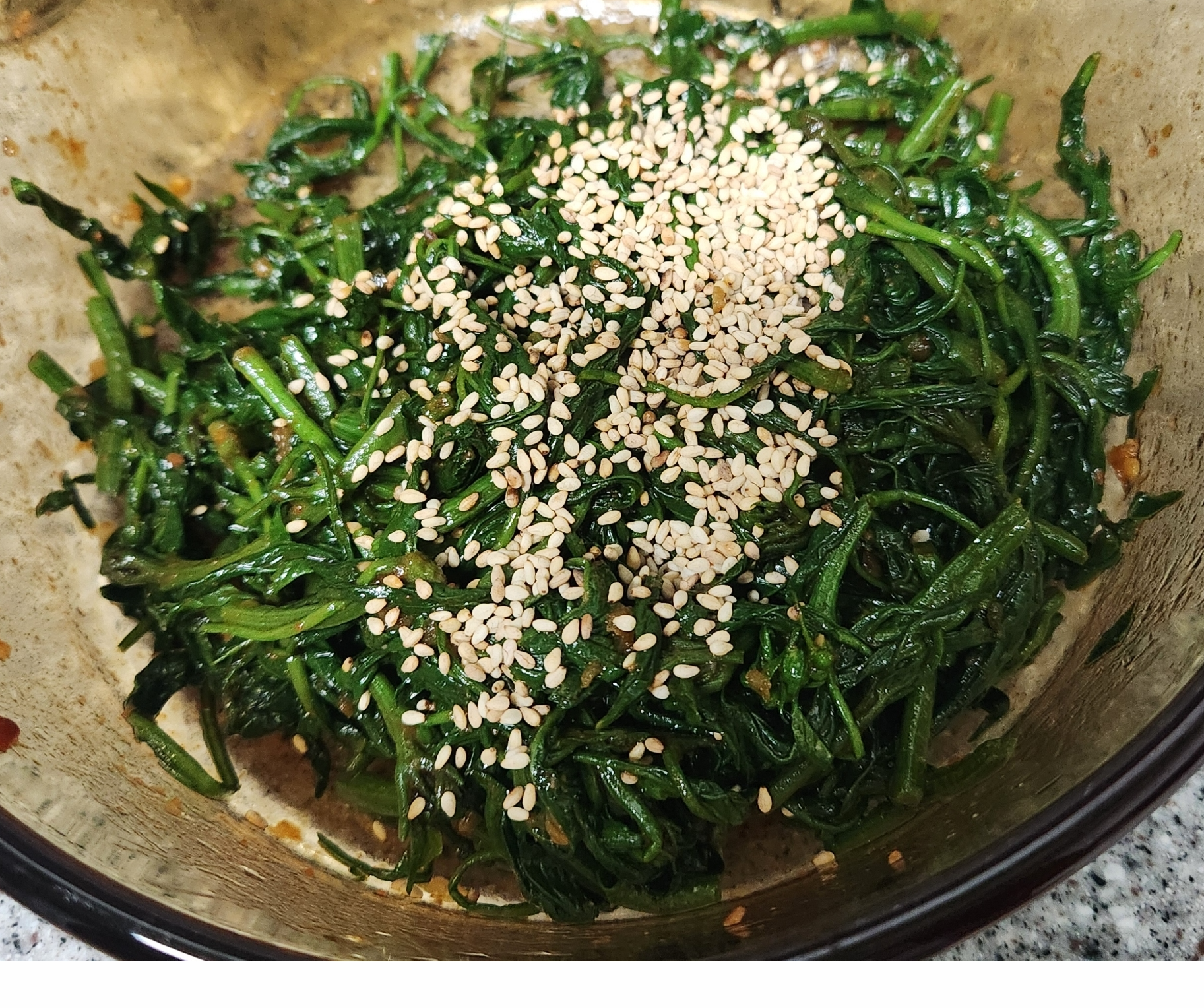 양념을 넣어 고춧잎을 무치고 있는 이미지