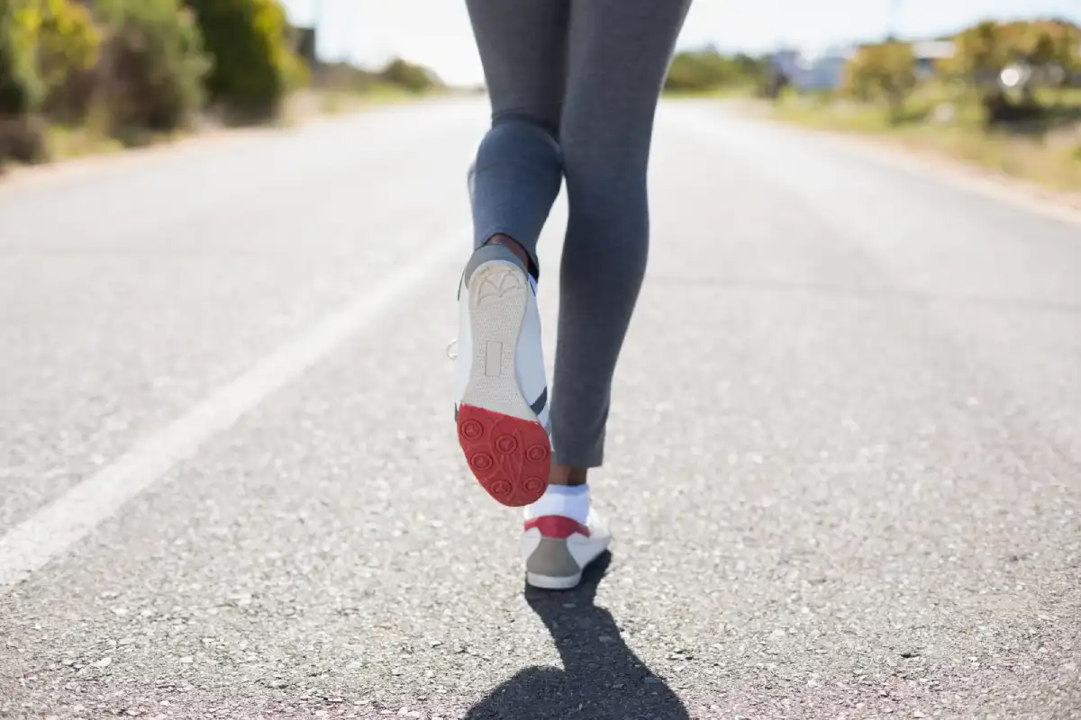 A slender woman running along a wide road